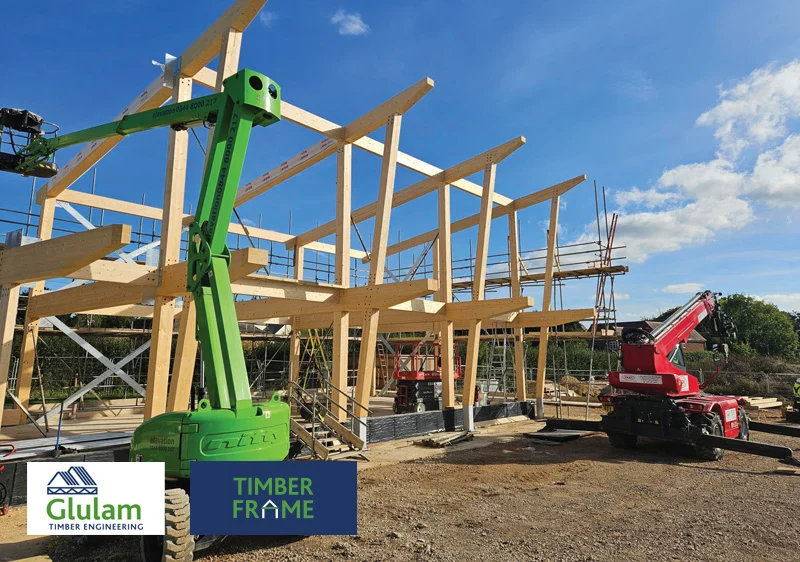 timber frame under construction with two cranes